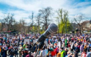 Microphone on the stage with a blurry crowd awaiting a speaker